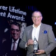 Clark Dumont in a sportcoat holding a crystal award.